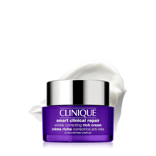 Clinique Smart Clinical Repair Wrinkle Correcting Rich Cream in a purple jar with a reflective silver lid, shown with a dollop of white cream behind it on a white background.
