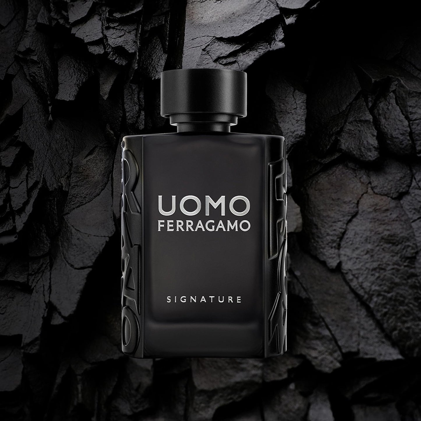 Black perfume bottle labeled 'Uomo Ferragamo' on a dark stone background