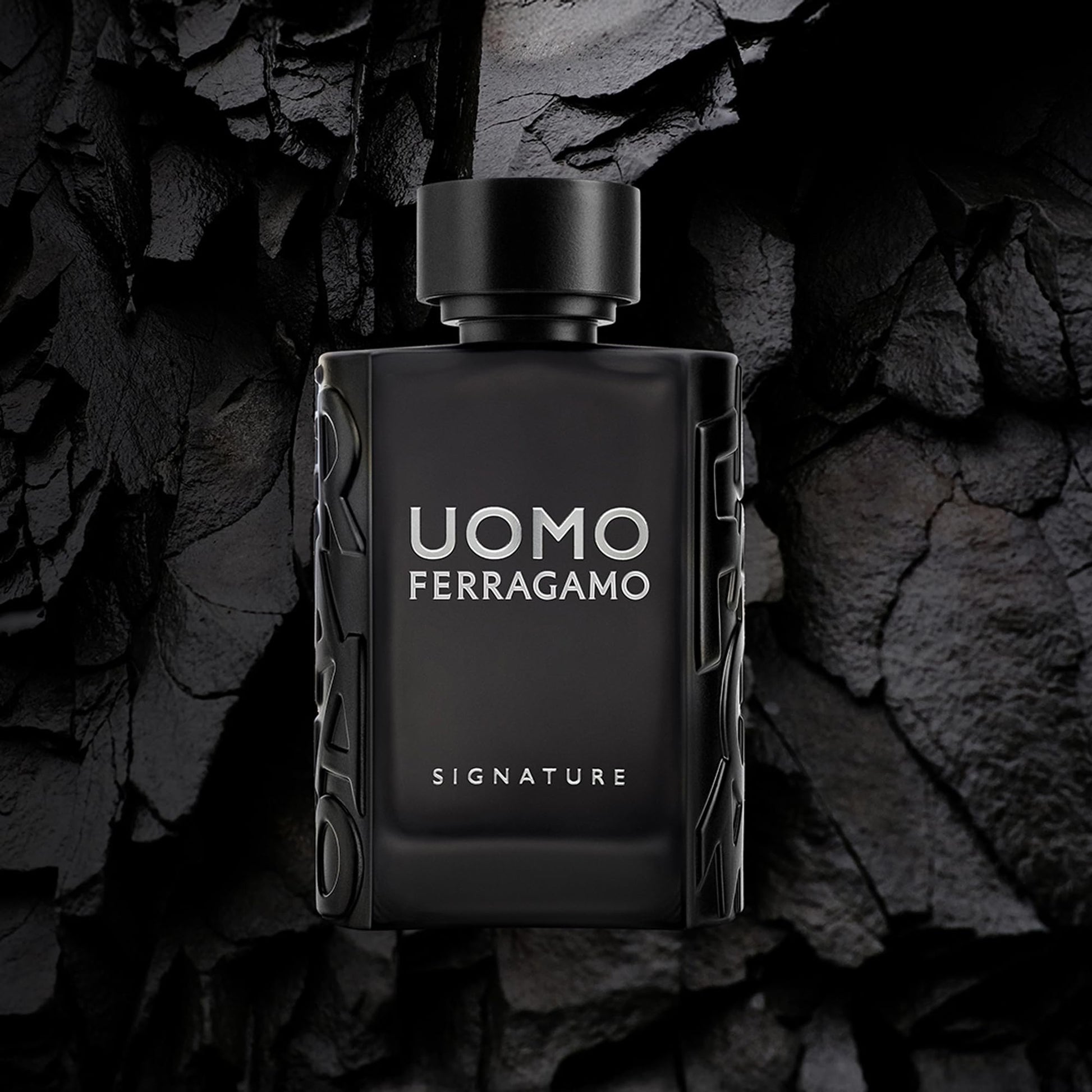 Black perfume bottle labeled 'Uomo Ferragamo' on a dark stone background