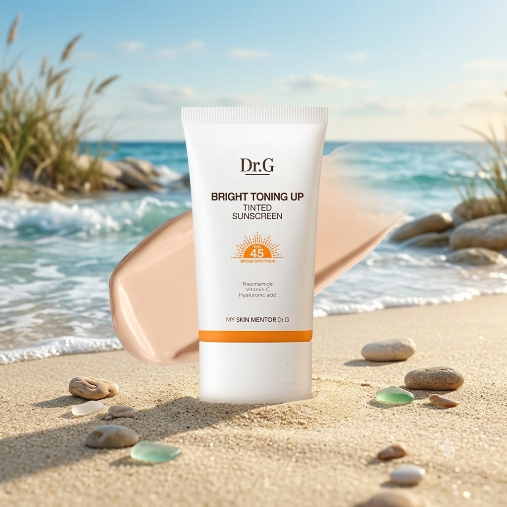 A tube of Dr.G Bright Toning Up Tinted Sunscreen stands on a sandy beach with ocean waves and rocks in the background.